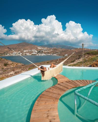 a person in a hammock hanging over a swimming pool at Agalia Luxury Suites in Tzamaria