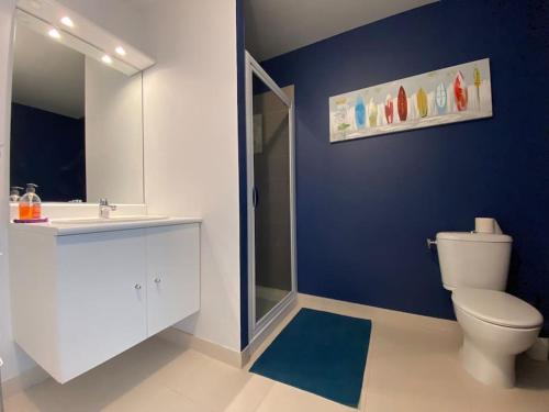 a bathroom with a white toilet and a blue wall at Superbe appartement terrasse, proche de la plage in Bénodet