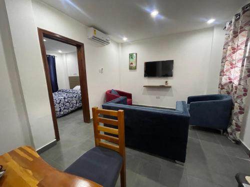 a room with chairs and a tv and a bed at American mall in Accra