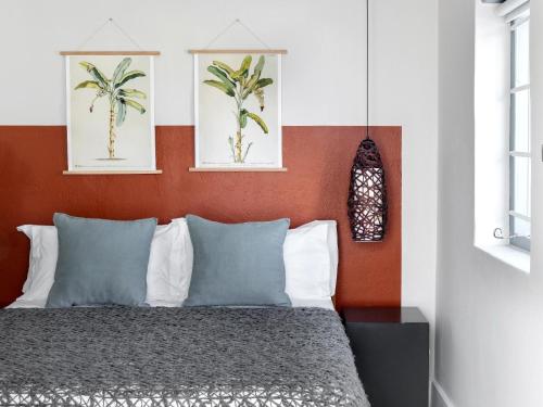 een slaapkamer met een bed met een oranje muur bij Greyton Lodge in Greyton
