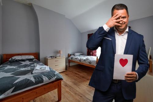 un homme en costume tenant un papier avec un cœur dessus dans l'établissement Maintenance, Transport, Medical Teams Bargain, 3 Bed Detached House, Mold, Sleeps 1 to 5, à Mold