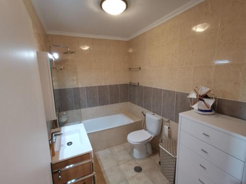 a bathroom with a tub and a toilet and a sink at Casa na onda Sonho da Baia in São Martinho do Porto