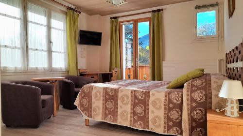 a bedroom with a bed and chairs and windows at Hôtel Bellier in La Chapelle-en-Vercors