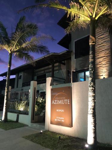 a sign in front of a building with palm trees at Pousada Azimute in Torres