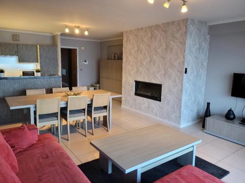 a living room with a couch and a table and a fireplace at Beach Palace in Middelkerke