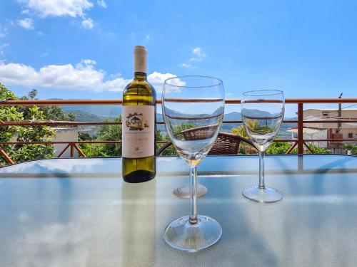 AGIOS PETROS APARTMENTS في Ágios Pétros: زجاجة من النبيذ وكأسين من النبيذ على الطاولة