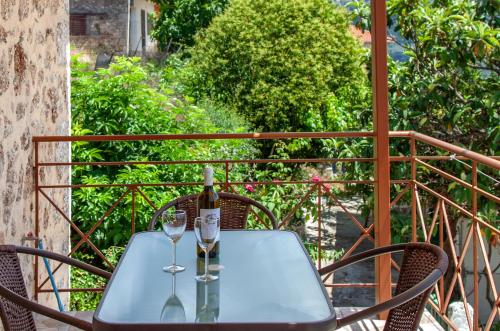 AGIOS PETROS APARTMENTS في Ágios Pétros: طاولة مع زجاجة من النبيذ وكأسين