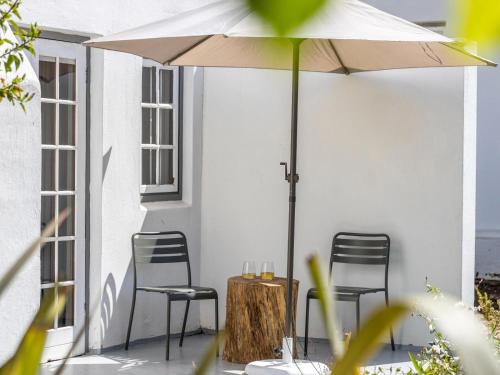 a table and chairs under an umbrella on a patio at Greyton Lodge in Greyton