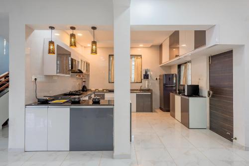 a large kitchen with white cabinets and appliances at Cosmicstays Ekantam - Serene Solitude With Inspiring Views at Velhe in Jadhavwadi