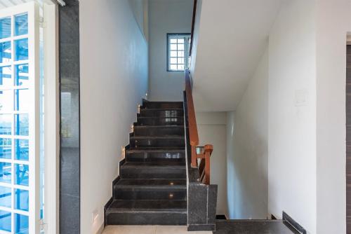 a staircase in a house with black stairs and a window at Cosmicstays Ekantam - Serene Solitude With Inspiring Views at Velhe in Jadhavwadi