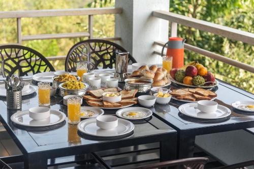 a table with breakfast foods and drinks on it at Cosmicstays Ekantam - Serene Solitude With Inspiring Views at Velhe in Jadhavwadi