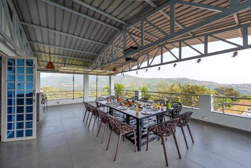 a dining room with a table and chairs on a balcony at Cosmicstays Ekantam - Serene Solitude With Inspiring Views at Velhe in Jadhavwadi