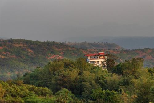 a house on top of a hill with trees at Cosmicstays Ekantam - Serene Solitude With Inspiring Views at Velhe in Jadhavwadi