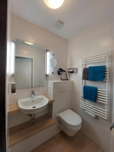 a white bathroom with a sink and a toilet at Hotel Purucker in Kulmbach