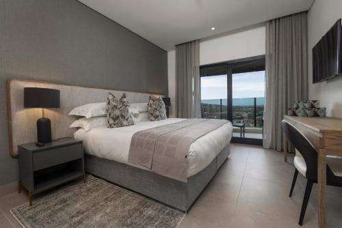 a bedroom with a bed and a desk and a window at 2202 Oceans Apartment - by Stay in Umhlanga in Durban