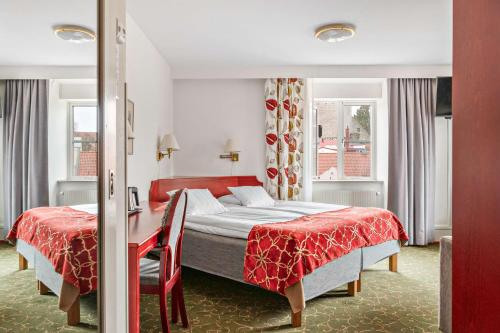 a bedroom with two beds and a red bedspread at Best Western Strand Hotel in Visby