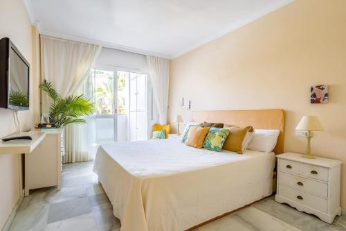 ein Schlafzimmer mit einem großen weißen Bett und einem Fenster in der Unterkunft OleHolidays Señorío Gonzaga junto a Puerto Banús in Marbella