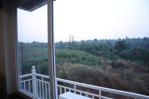 a window with a view of a field and trees at Hotel Wayfarer in Porvorim