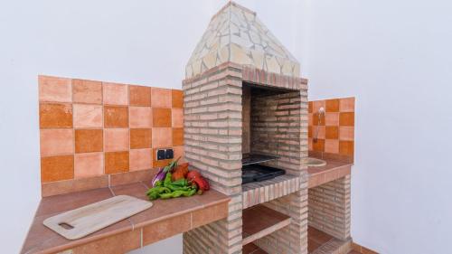 una cocina con una chimenea de ladrillo con verduras en la barra en Casa Verde de Elena Benalauría by Ruralidays, en Benalauría