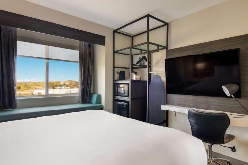 ein Hotelzimmer mit einem Bett, einem Schreibtisch und einem TV in der Unterkunft Sleep Inn & Suites Clarion, PA near I-80 in Clarion