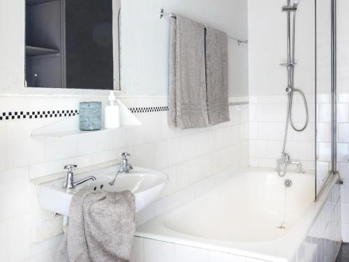 a white bathroom with a sink and a bath tub at Greyton Lodge in Greyton
