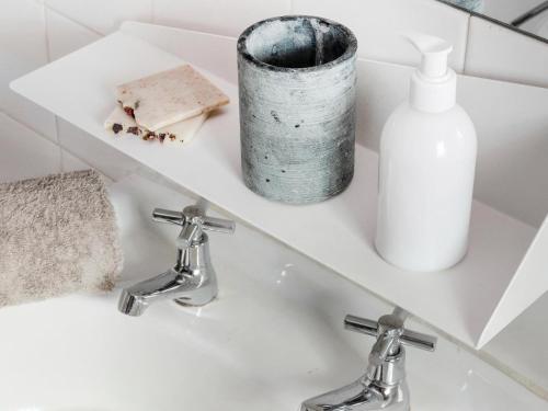 a bathroom sink with two faucets and a bottle of soap at Greyton Lodge in Greyton