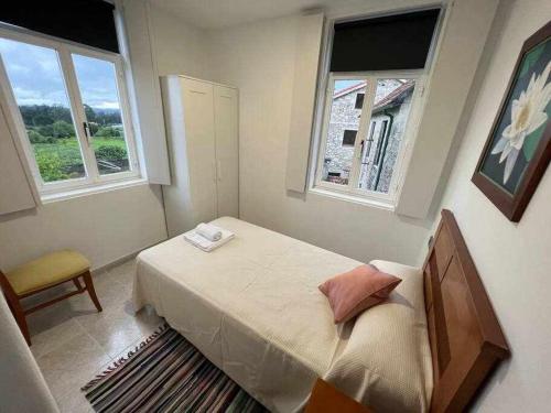 um pequeno quarto com uma cama e 2 janelas em Apartamento A em Irijoa