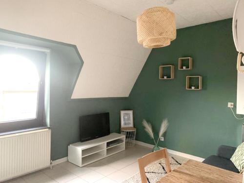 a living room with a television and a green wall at Studio with city view at Saint Nicolas in Ans