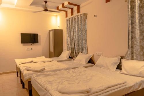 a group of four beds in a room at Anandvan Beach Resort in Alibaug