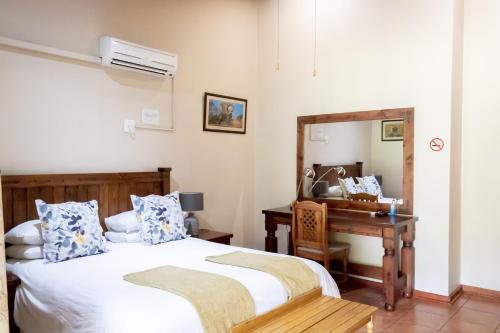 a bedroom with two beds and a desk and a mirror at Sunbird Lodge in Phalaborwa