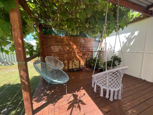 a porch with two chairs and a swing at Shoal Bay Serenity Beach Cottage Newly Renovated in Shoal Bay