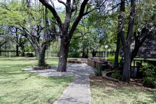 a walkway in a park with trees and benches at Sunbird Lodge in Phalaborwa