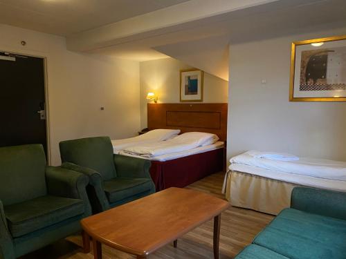 a hotel room with two beds and a table and chairs at Park Hotel Vossevangen in Vossevangen