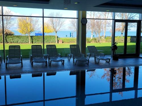 un grupo de sillas sentadas junto a una piscina de agua en Club218 Wellness Apartments, en Siófok