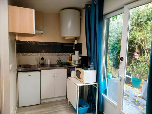 uma pequena cozinha com armários brancos e uma janela em La Lilloise Villeneuve D'Ascq GD STADE Mauroy em Villeneuve d'Ascq