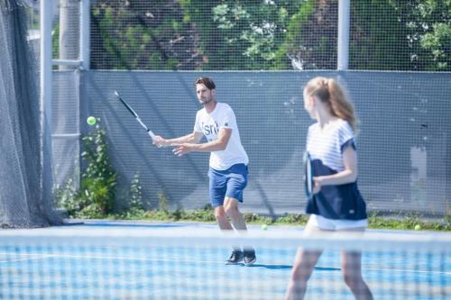 a man and a girl playing tennis on a tennis court at MALIBU HOTEL in Zushi