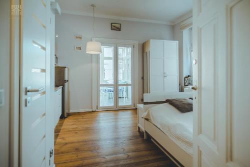 a white bedroom with a bed and a window at Art Nouveau Weranda in Sopot