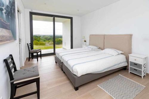 a bedroom with a large bed and a large window at Casa Barbónica piscina privada in Bairro do Lobo