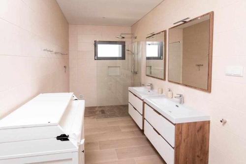 uma casa de banho branca com 2 lavatórios e um espelho em Casa Barbónica piscina privada em Bairro do Lobo