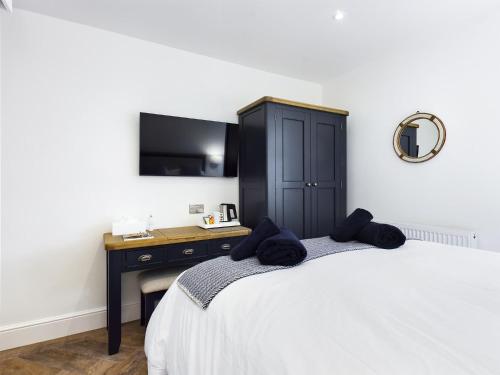 a bedroom with a bed with a desk and a tv at Driftwood Boutique Guest House in Rhosneigr