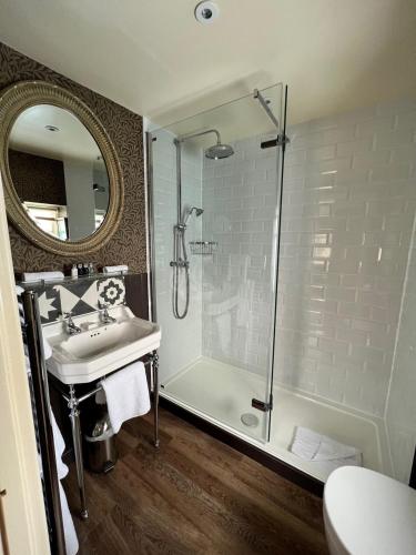 a bathroom with a shower and a sink and a mirror at The Broadway Hotel in Broadway