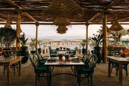 ein Restaurant mit Tischen und Stühlen und Blick auf den Strand in der Unterkunft Caravan by Habitas Agafay in Marrakesch