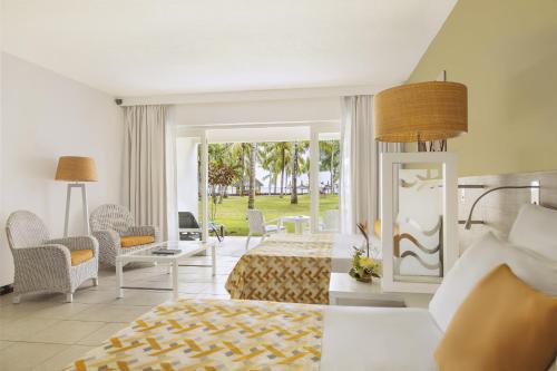 Victoria Beachcomber Resort & Spa في بوينتي أو بيتشيز: غرفة نوم بسرير وطاولة وكراسي