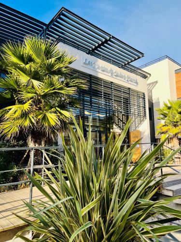 un bâtiment avec un palmier devant dans l'établissement Les Patios de St-Pierre, à Palavas-les-Flots