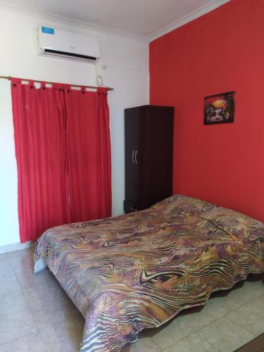 ein Schlafzimmer mit einem Bett und einer roten Wand in der Unterkunft Deptos Peumayen - Parking - Excelente Ubicacion - Full Equipado in Río Colorado