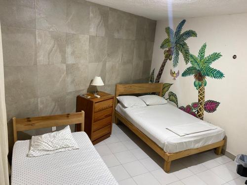 a bedroom with two beds and a palm tree mural at CASA BUGAMBILIAS in Cancún