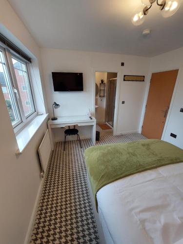 um quarto com uma cama, uma secretária e uma televisão em bankwellstreet em Manchester