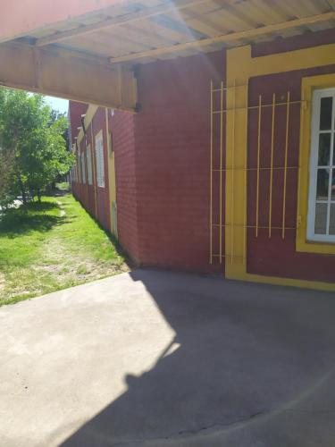 a school building with a yellow and red wall at Deptos Peumayen Familiar - Parking - Excelente Ubicacion - Full Equipado in Río Colorado