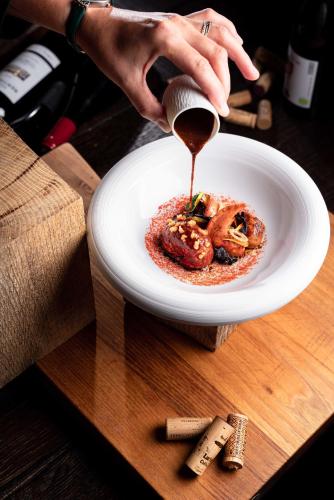 a person drizzling sauce onto a plate of food at La Ferme Saint Simeon Spa - Relais & Chateaux in Honfleur