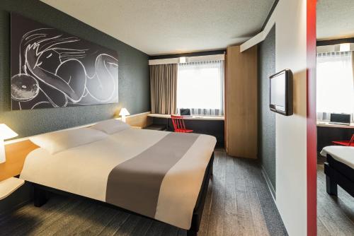 a hotel room with a bed and a tv at ibis München Parkstadt Schwabing in Munich